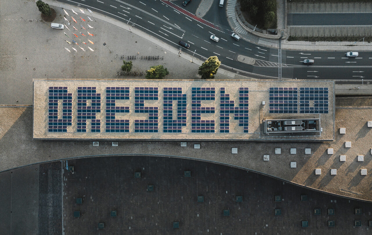 Auf dem Dach des Kongresszentrums befindet sich eine Photovoltaikanlage als Schriftzug „DRESDEN“. Foto: Sebastian Weingart (DML-BY) -- On the roof of the congress center there is a photovoltaic system as a lettering "DRESDEN". Photo: Sebastian Weingart (DML-BY)